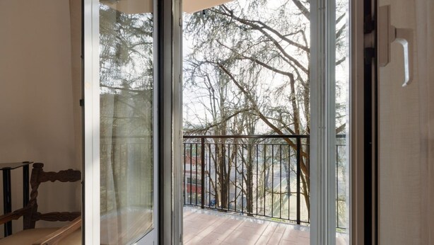 A room with a sliding glass door leading to a balcony with a metal railing, a wooden bench, and a doormat. - GuestHost - Comfortable 100sqm flat located on the fourth floor (with lift), equipped with kitchen, living area, two bathrooms and two bedrooms that can accommodate up to 4 people. A short walk from Lambrate and Udine stations, it is conveniently located (Milano)