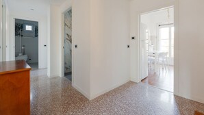 A spacious hallway with a wooden desk, a bathroom with a toilet and sink, and a dining area with chairs and a table. - GuestHost - Comfortable 100sqm flat located on the fourth floor (with lift), equipped with kitchen, living area, two bathrooms and two bedrooms that can accommodate up to 4 people. A short walk from Lambrate and Udine stations, it is conveniently located (Milano)