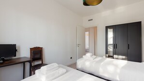 A hotel room with a bed, a desk with a television, a chair, and a wardrobe. - GuestHost - Comfortable 100sqm flat located on the fourth floor (with lift), equipped with kitchen, living area, two bathrooms and two bedrooms that can accommodate up to 4 people. A short walk from Lambrate and Udine stations, it is conveniently located (Milano)