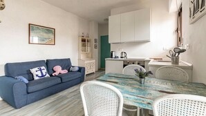 A compact living space with a sofa, dining table, and kitchenette. - GuestHost - Pineta di Ponente Apartment (Viareggio)