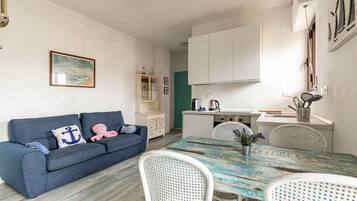 Un espacio habitable compacto con sofá, mesa de comedor y kitchenette.