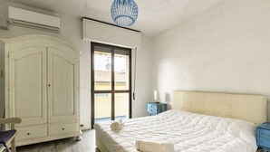 A bedroom with a bed, a wardrobe, a chair, a nightstand, and a window. - GuestHost - Pineta di Ponente Apartment (Viareggio)