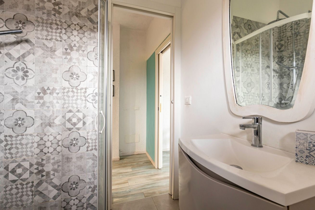 A bathroom with patterned tiles, a sink, and a mirror.