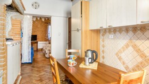 Uma cozinha com mesa de madeira, cadeiras, chaleira e relógio na parede.