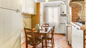 Cozinha com mesa de jantar, cadeiras, chaleira e radiador.