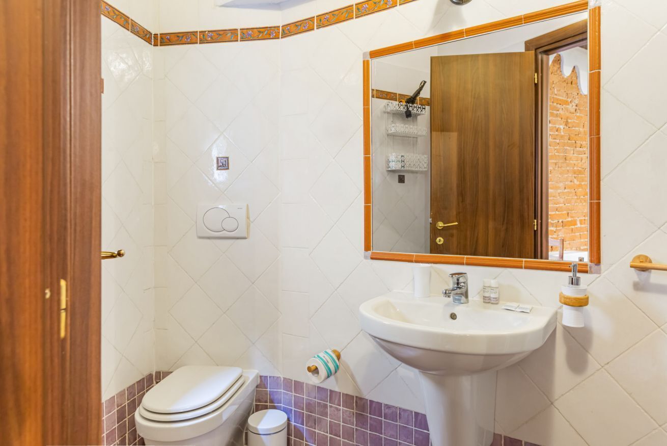A bathroom with a toilet, sink, and mirror.