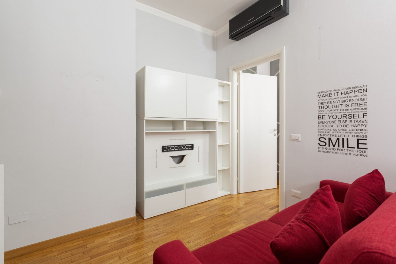 Une chambre moderne avec un placard intégré blanc, un canapé rouge et une citation inspirante peinte sur le mur.