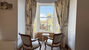 A corner room with two wooden chairs, a small table, and a bay window with curtains. - 45 Eskin Street  - sleeps 6 guests  in 3 bedrooms (Central Keswick)
