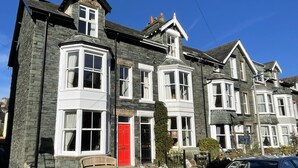 A row of stone houses with white-framed windows and a red door. - 45 Eskin Street  - sleeps 6 guests  in 3 bedrooms (Central Keswick)