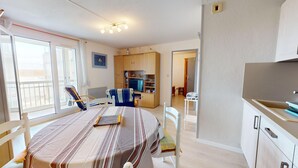 Un espacio habitable compacto con una mesa de comedor, sillas, un televisor y una kitchenette.