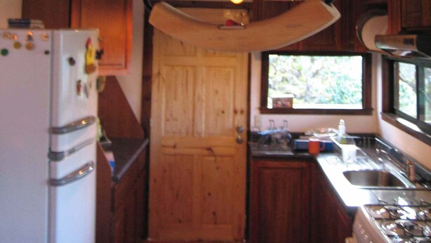 Une cuisine avec des meubles de rangement en bois, un réfrigérateur blanc, une cuisinière et un luminaire suspendu.
