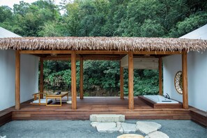 A wooden structure with a thatched roof, stone steps, and a seating area with cushions. - Changtai Fruit Hostel (Zhangzhou)