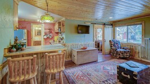 A rustic kitchen with wooden furniture, a dining area with a patterned rug, and a cozy seating area with a patterned chair. - Serene River Place Retreat Unit 2, 1-bedroom condo nestled along the river in Howard, CO. (Howard)