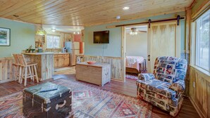 A cozy cabin interior with a wooden ceiling, a kitchen area, a dining space, and a living room with a patterned rug. - Serene River Place Retreat Unit 2, 1-bedroom condo nestled along the river in Howard, CO. (Howard)