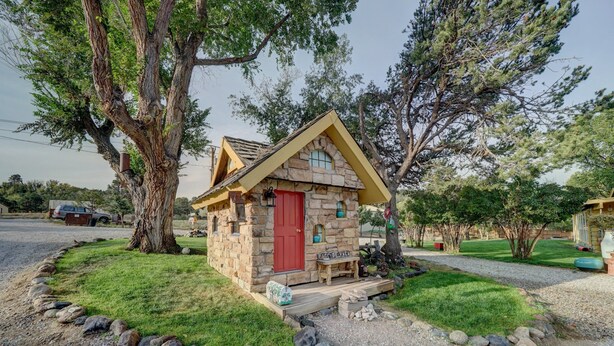 A small stone cabin with a red door, surrounded by a gravel path and a grassy area. - Serene River Place Retreat Unit 2, 1-bedroom condo nestled along the river in Howard, CO. (Howard)