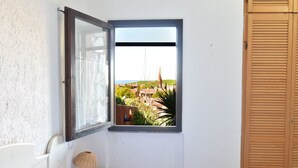 A bathroom with a window, a bed, and a bedside table with a lamp.