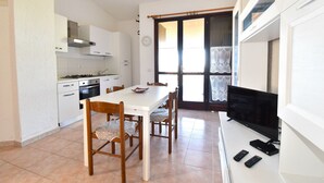 A compact kitchen with white cabinets, a stove, and a dining table with chairs.