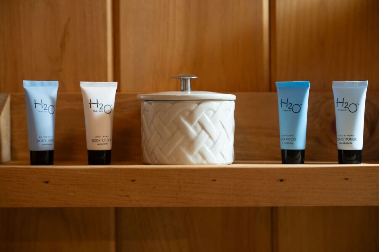 A wooden shelf with five H2O body care products, including a body lotion, shampoo, and conditioner.