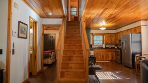 A wooden staircase leading to a second floor with a kitchen area on the right.