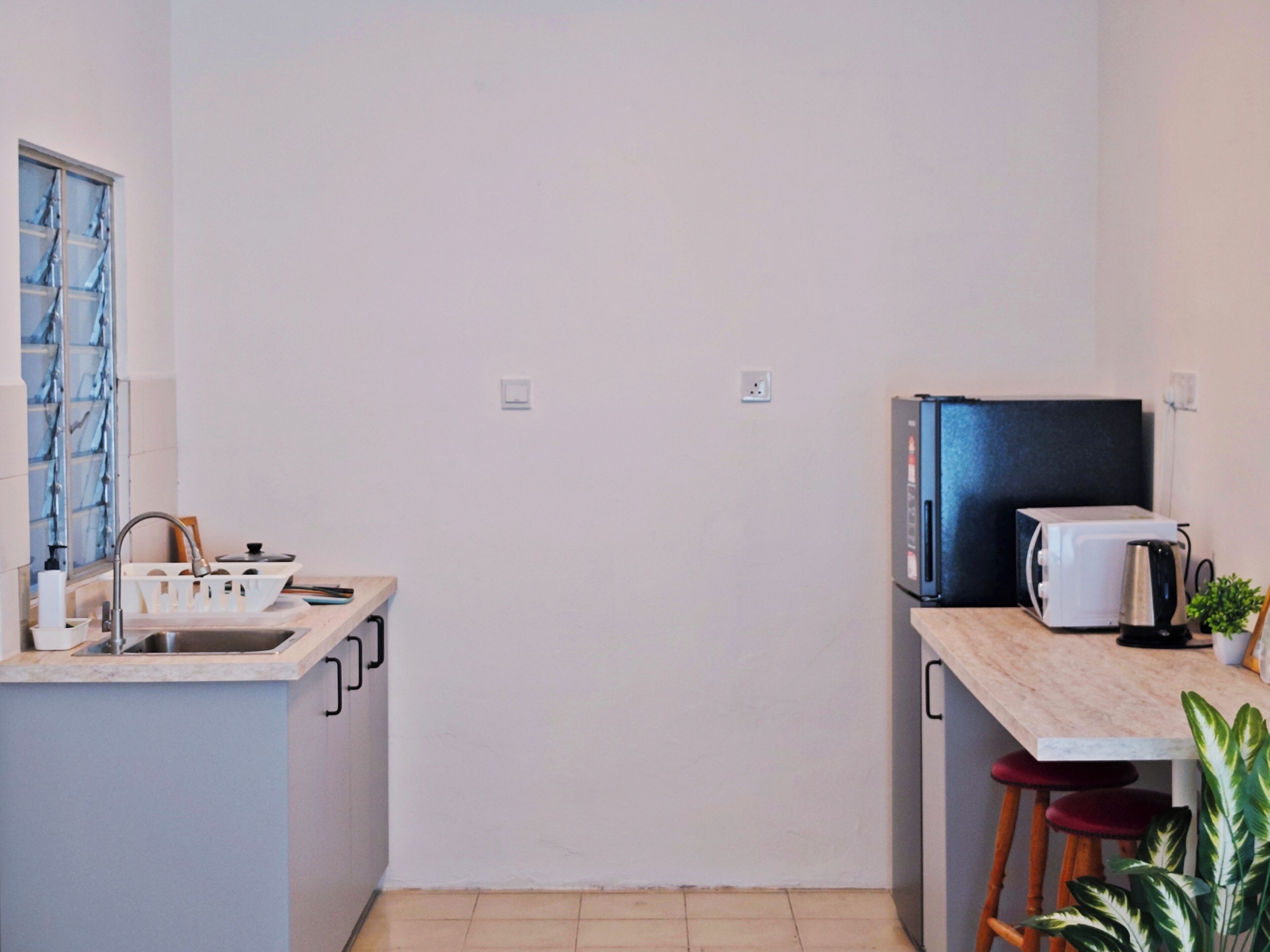 A compact kitchen with a sink, a microwave, and a toaster on the countertop.