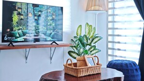 A living room with a TV displaying a nature scene, a lamp, a plant, and a small table. - Cosy Batu Kawan Homestay 12 pax ~ 5 mins to Design Village & IKEA ~ Entire Home (Simpang Ampat)