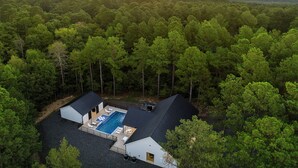 Una casa con piscina rodeada de bosque.