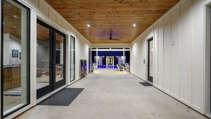 Un pasillo con puertas de vidrio, techo de madera y una zona iluminada en azul al final.