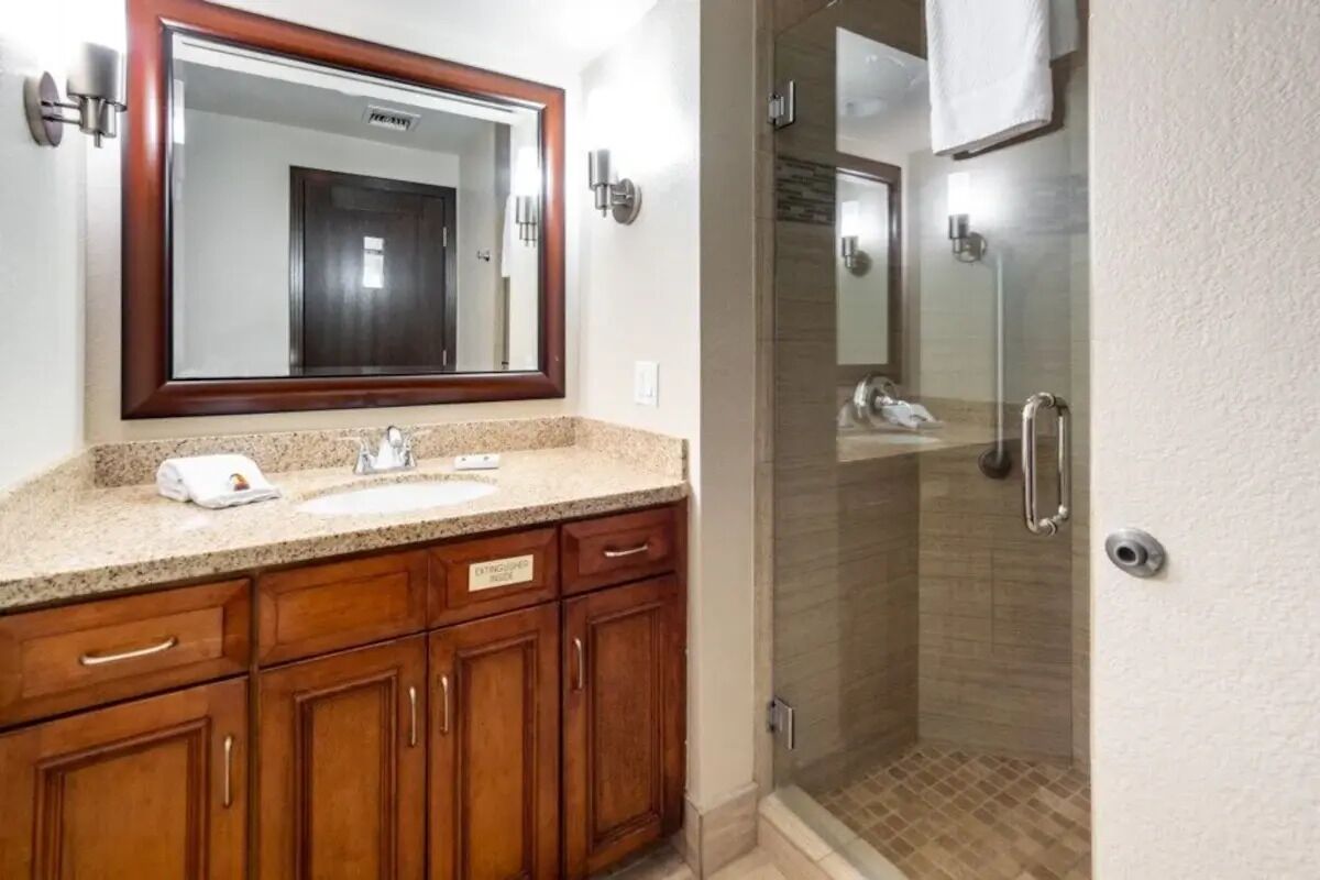 A bathroom with a wooden vanity, a large mirror, and a glass shower enclosure.
