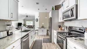 A modern kitchen with white cabinets, a built-in oven, a microwave, and a stove.