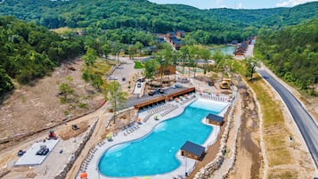 Een resort met een groot zwembad, loungegedeeltes en uitzicht op de omliggende beboste heuvels.