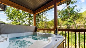 Un jacuzzi en una terraza de madera con vistas a árboles y un cielo despejado.