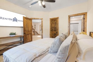 Un dormitorio con una cama, un ventilador de techo y un letrero en la pared.