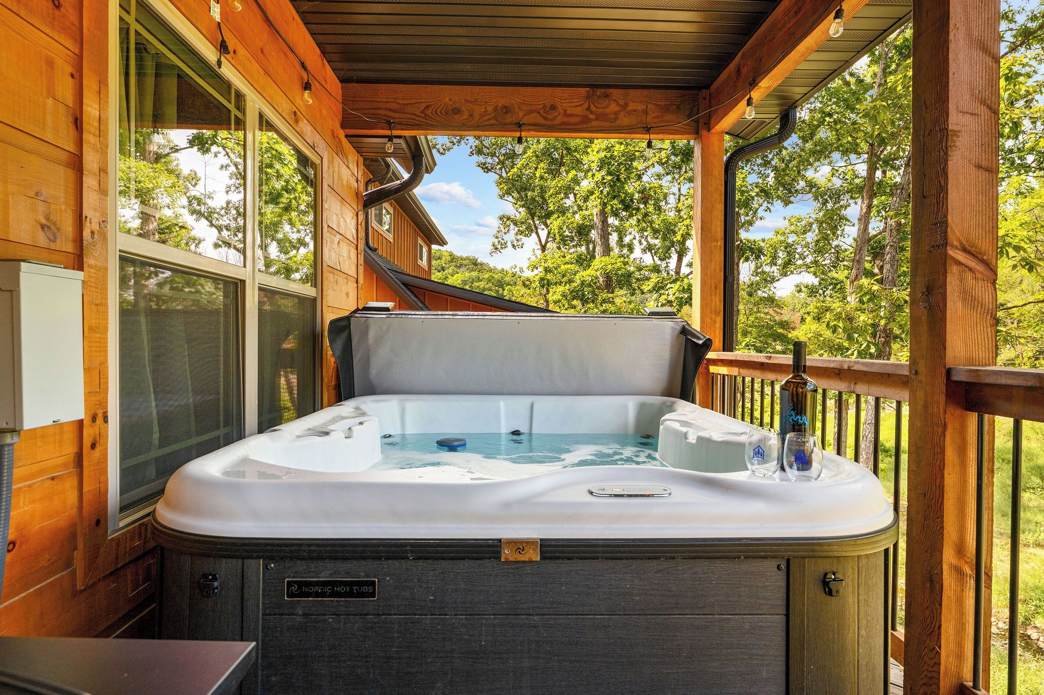 Un bain à remous sur une terrasse en bois, avec vue sur les arbres.