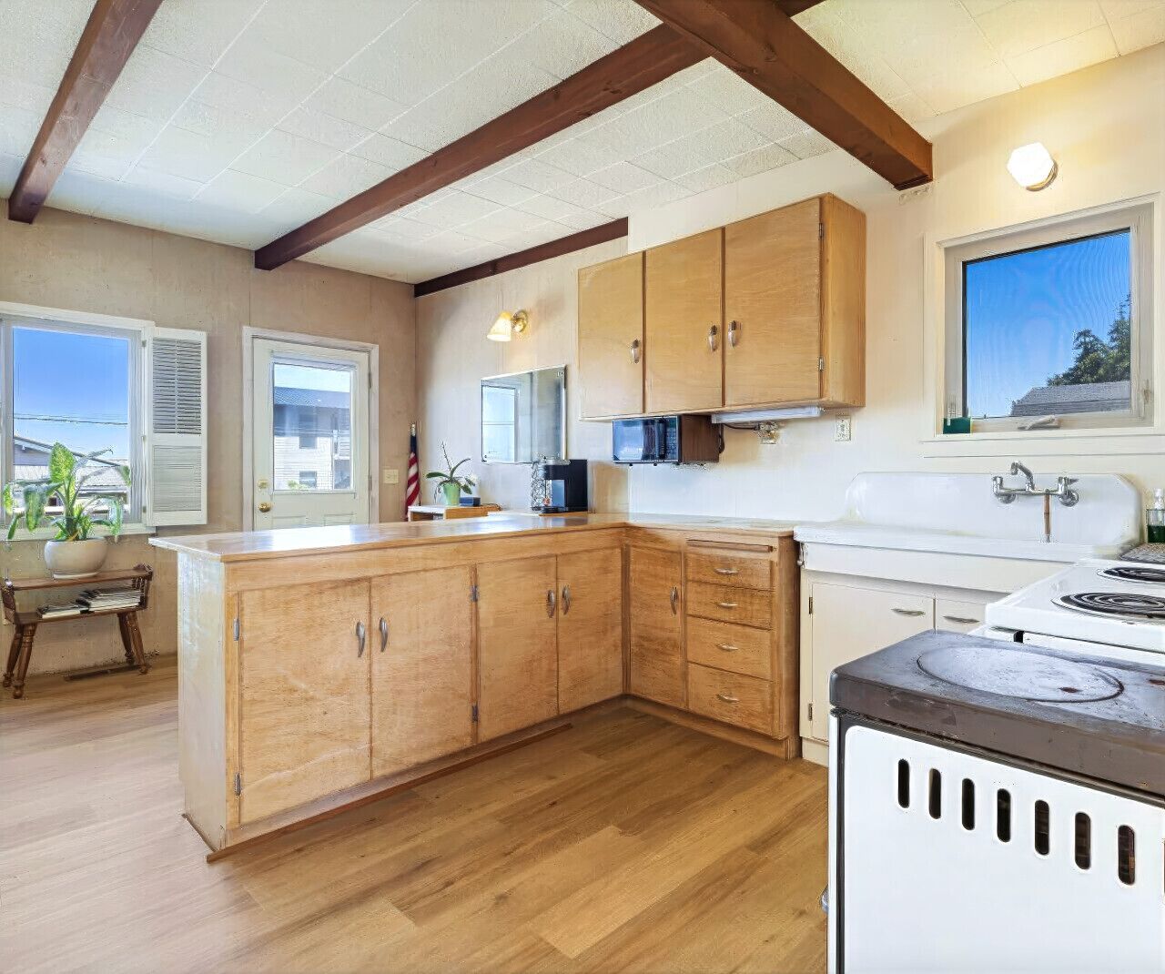 A kitchen with wooden cabinets, a stove, and a window with blinds.