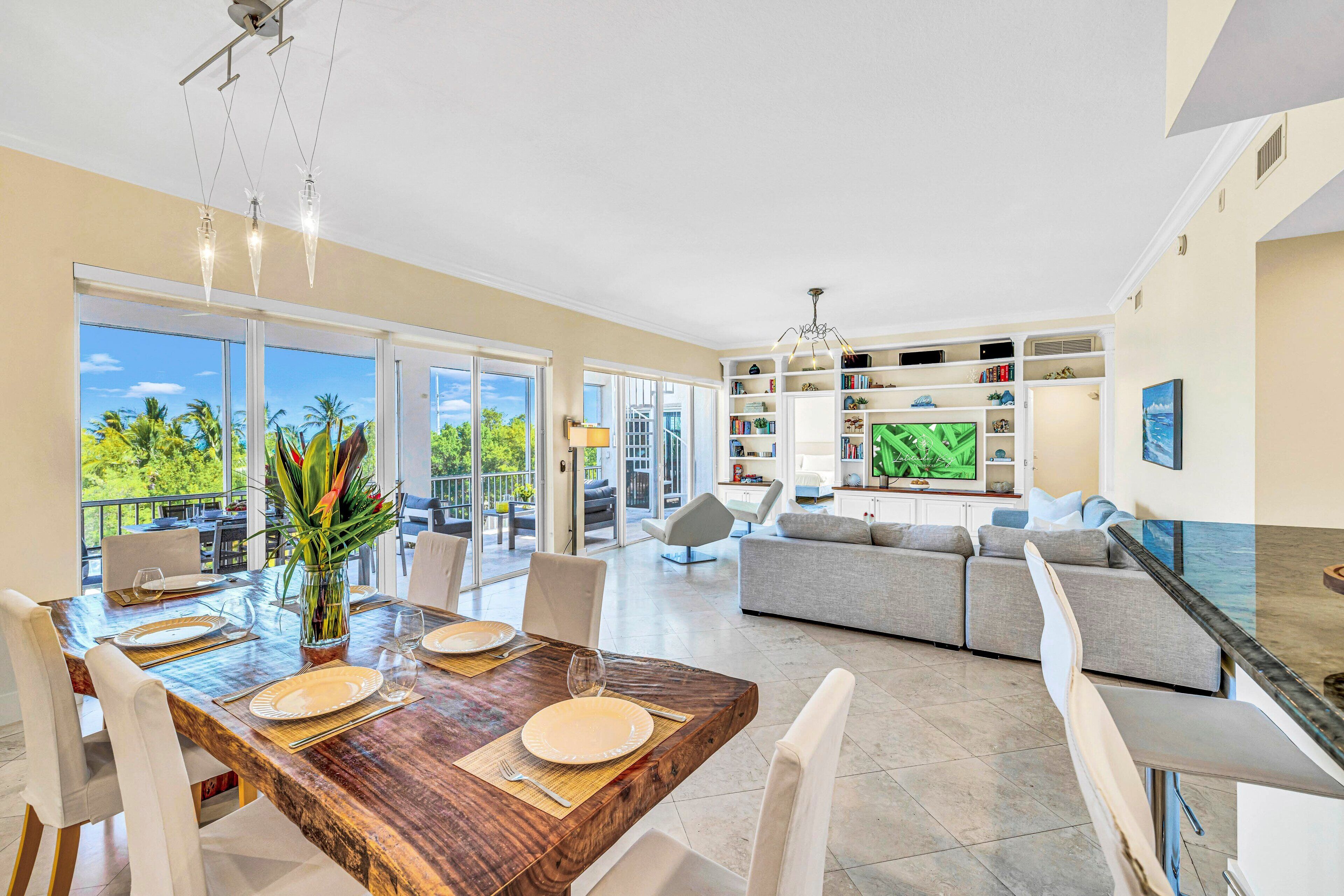 A spacious living area with a dining table set for four, a sofa, and a television.