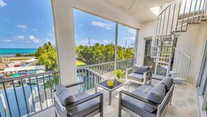 A balcony with a view of the sea, a dining table with chairs, and a staircase. - Ocean View Penthouse | Retreat amenities: tennis court, heated Pool | Vista Key Two (Islamorada)