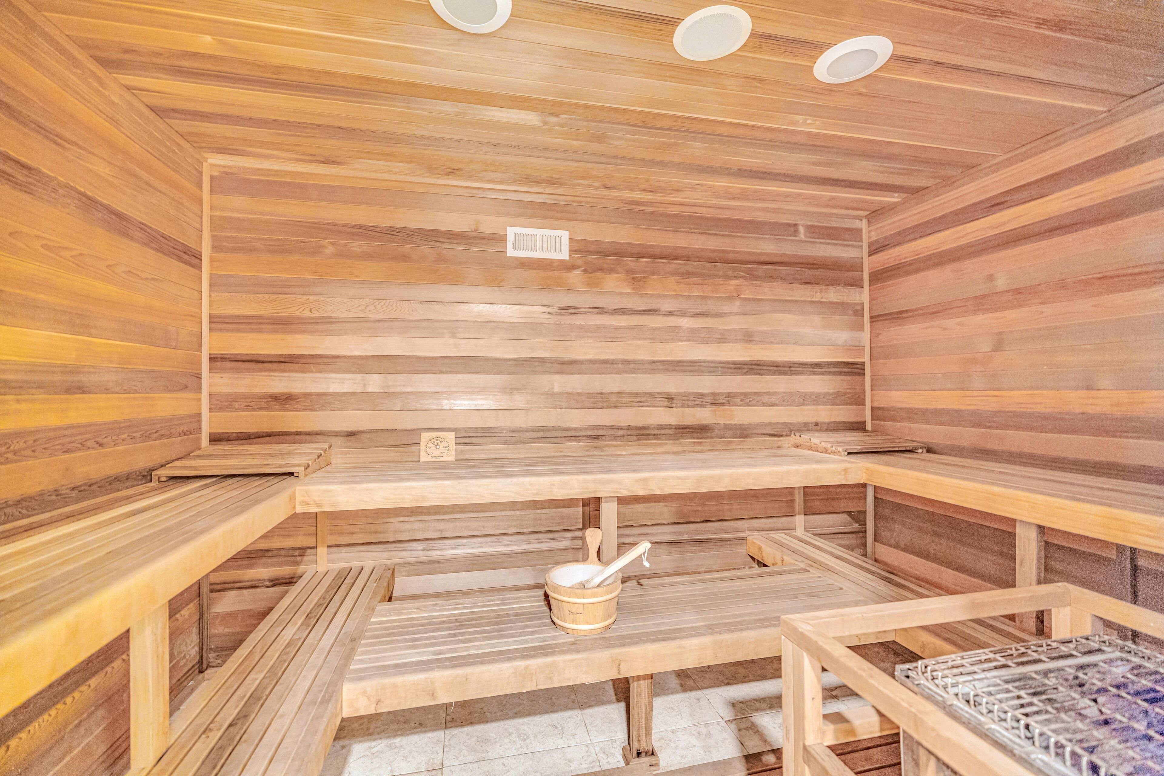 Una sauna con bancos de madera y un cubo de madera con una cuchara.