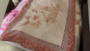 Een bed met een bloemenprint sprei en een decoratieve rand.