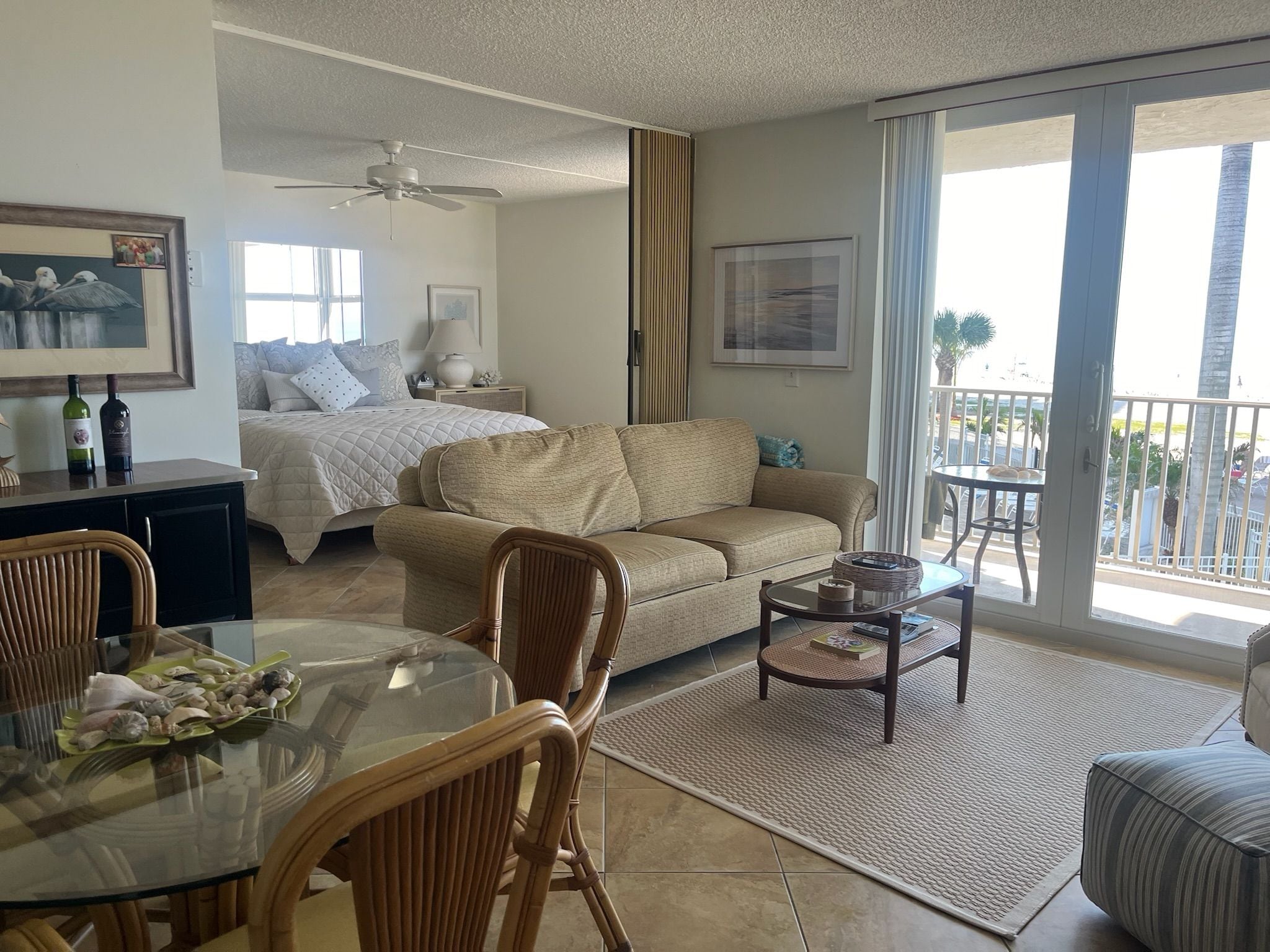 Ein helles Wohnzimmer mit einer Couch, einem Esstisch mit Stühlen, einem Couchtisch und einem Balkon mit Aussicht.