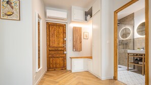 A hallway with a wooden door, white cabinets, and a bathroom with a glass shower and a round mirror. - Luxurious Retreat in Old Antibes & beach (Antibes)