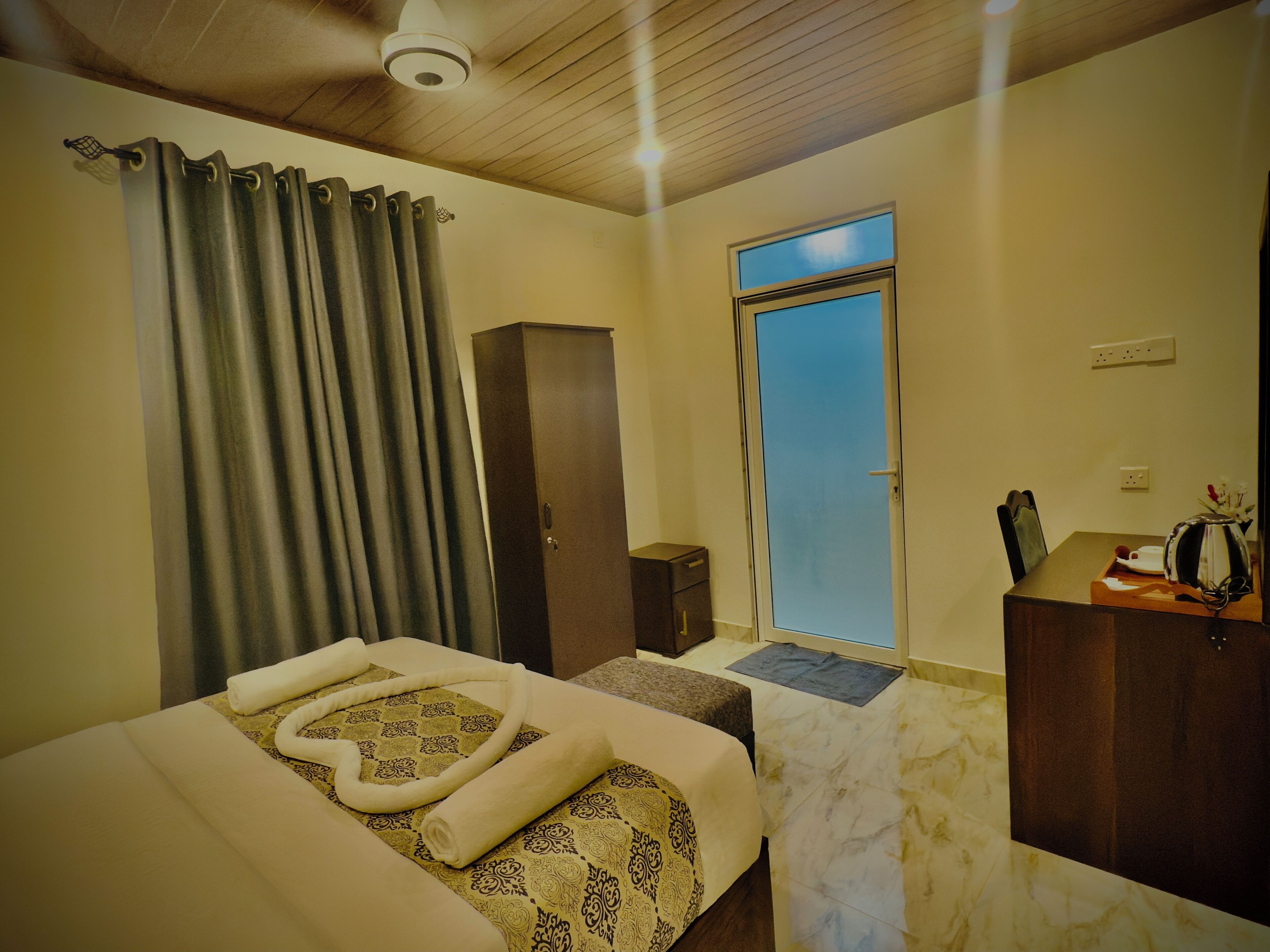 Ein Hotelzimmer mit einem Bett, einem Schrank, einem Schreibtisch mit Wasserkocher und einem Fenster mit Blick.