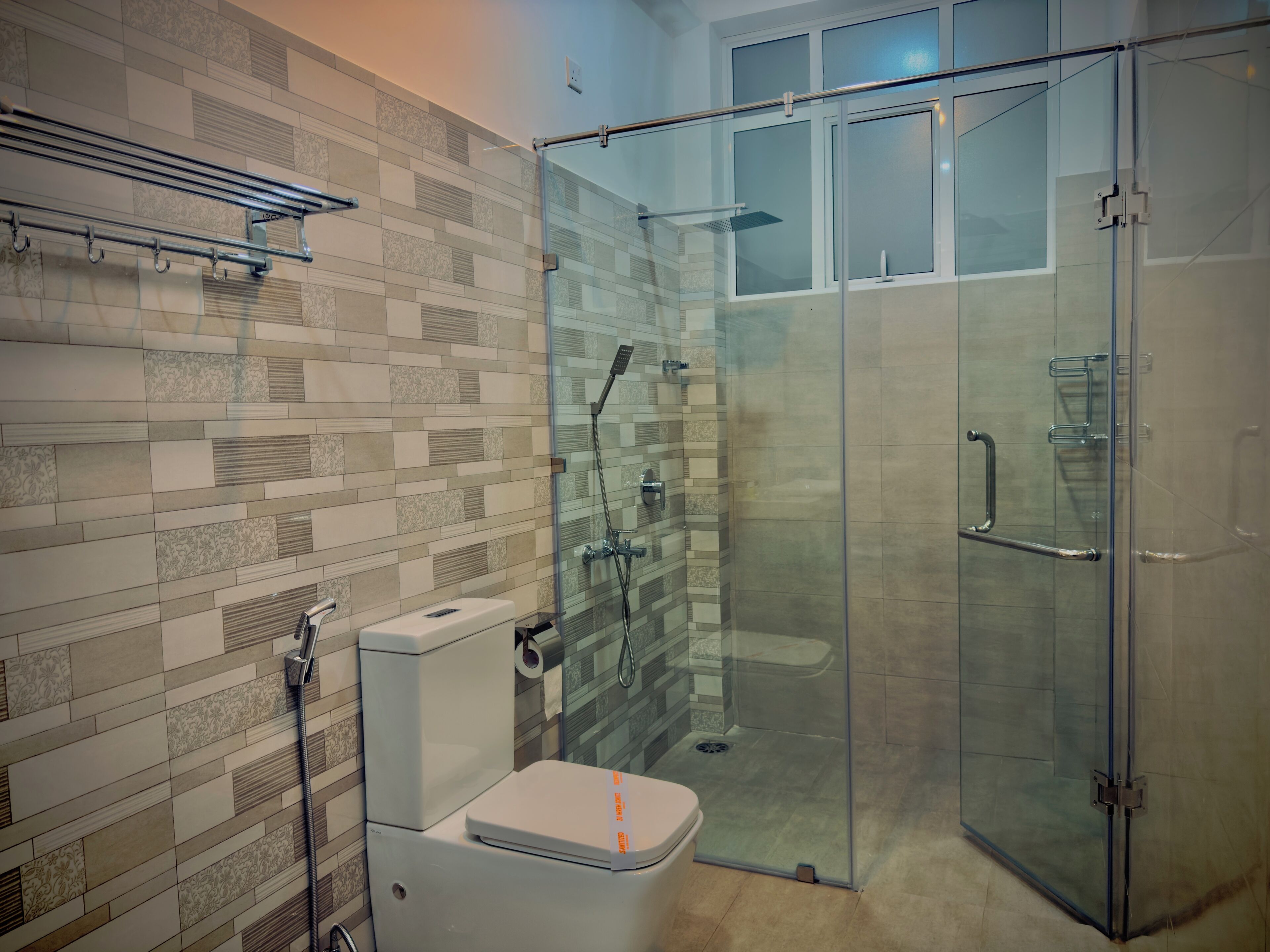 Een moderne badkamer met een douchecabine van glas, een toilet en een handdoekrek.