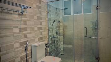 Een moderne badkamer met een douchecabine van glas, een toilet en een handdoekrek.