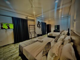 Habitación de hotel con dos camas, televisión, armario, espejo y ventilador de techo.