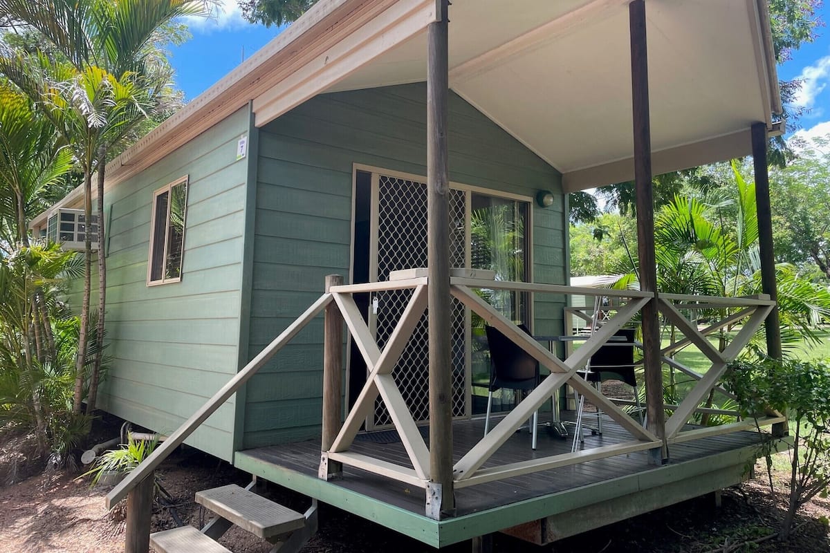A small, single-story house with a porch, a screened door, and a window.