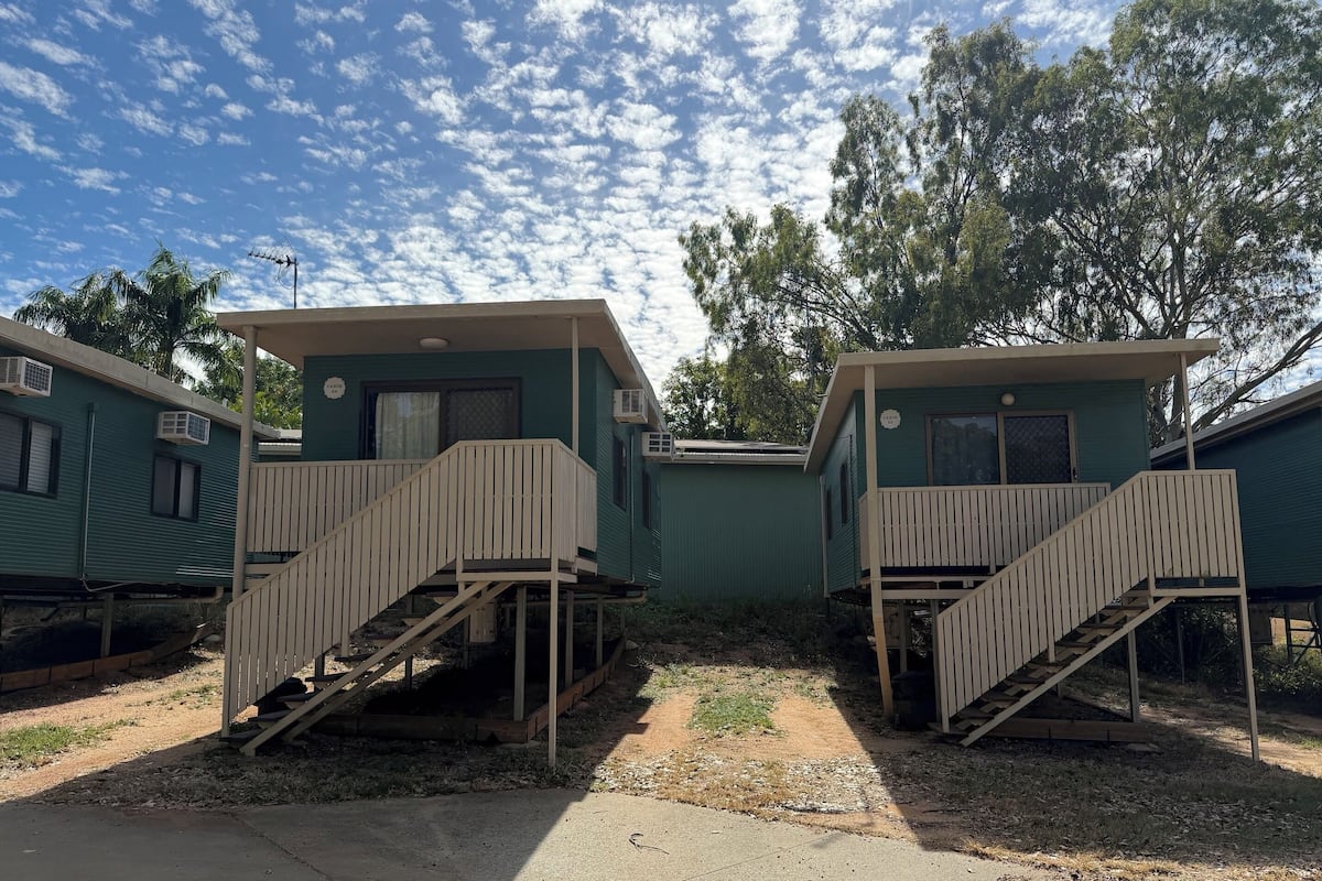 Two mobile homes with external staircases, air conditioning units, and a clear sky.