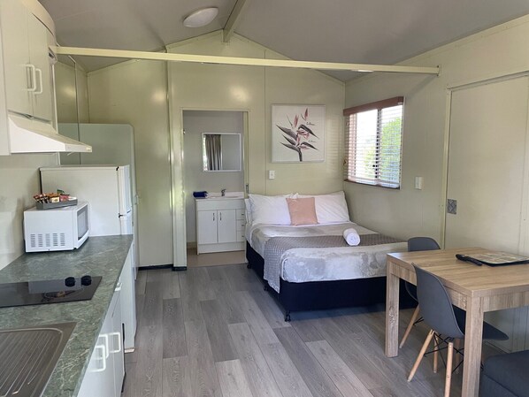 Une pièce de taille modeste comprenant un lit, une petite kitchenette, un coin repas et une salle de bain.