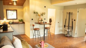 A modern kitchen with a dining area, wooden flooring, and a sofa with cushions. - Charming Fraser Cottage Getaway in Insh,  Couples Getaway near Aviemore. (Kincraig)