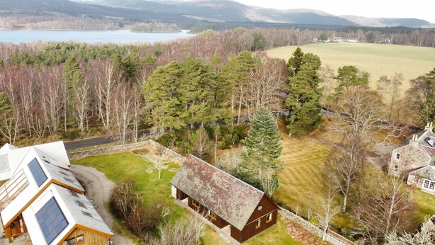 A rural property with a large house, a smaller cabin, and a view of a lake and mountains. - Charming Fraser Cottage Getaway in Insh,  Couples Getaway near Aviemore. (Kincraig)