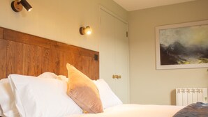A neatly made bed with white linens and a wooden headboard, a wall-mounted artwork depicting a stormy landscape, and a white radiator. - Charming Fraser Cottage Getaway in Insh,  Couples Getaway near Aviemore. (Kincraig)